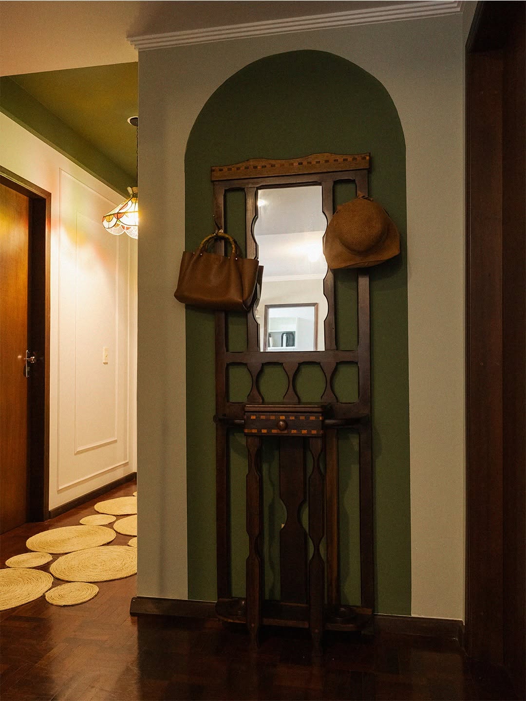 Hall com parede verde em arco e cabideiro antigo